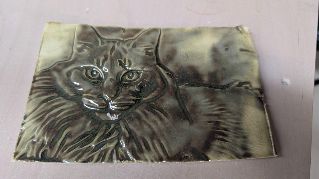 A pottery tile featuring a textured relief of a cat named Casper